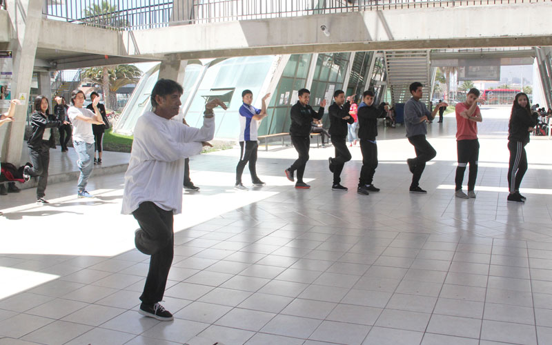 Profesor liderando postura de brazos y pierna en Clase de Tai Chi.